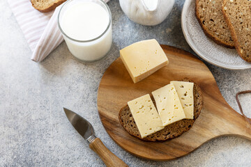 Healthy food concept, breakfast, superfood. Fresh whole grain bread with cheese and a glass of almond milk on stone table. Copy space.