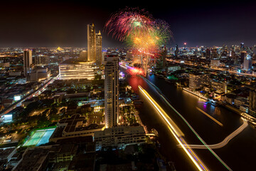 Modern buildings in the city with water reflection, firework, light show at night time.