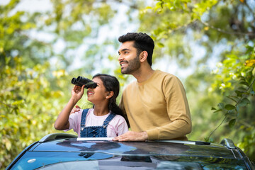 Happy father with daughter watching nature by using binocular during summer camp - concept of...