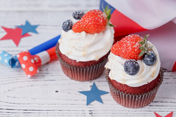 Sweet cupcakes with blueberries and strawberry , usa flag on white wooden background