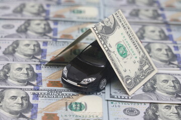 Model of a black car on the background of a hundred dollar bill, auto insurance, credit.