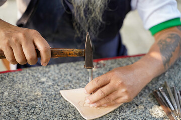 Closeup hand of leather craftsman is carefully to make a leather product for a customer., Leather craftsman concept.