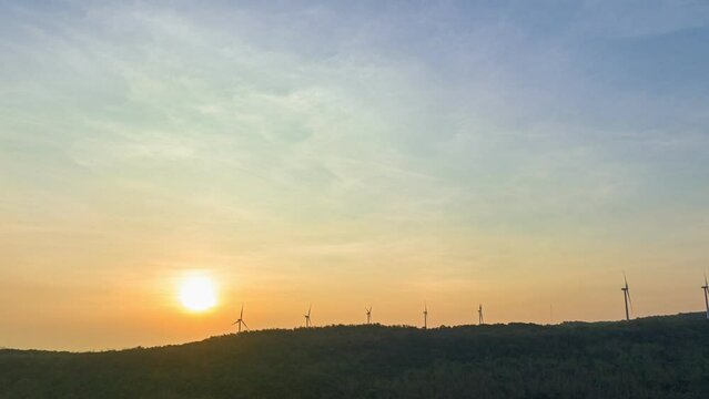 aerial hyperlapse view beautiful sunrise above wind turbines..scenery sky in the morning above the large dam..wind turbine on the top of mountain.Wind power generates electricity. Clean energy
