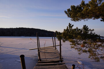 Broken wooden pier on a frozen lake