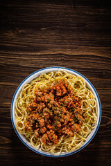 Spaghetti with minced meat, tomato sauce, parmesan cheese and seasonings served on wooden table

