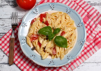 Delicious plate of Greek pasta with feta cheese, tomato, Taggiasca olives, basil and oregano.