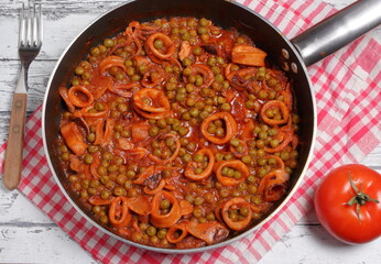 Stewed squid with peas cooked in a non-stick pan photographed from above.