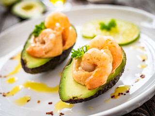Avocado with fried prawns on and cocktail sauce on wooden background
