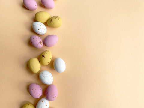 Easter quail eggs over beige background. Spring holidays concept with copy space. Easter decorative composition of chocolate eggs. Top view
