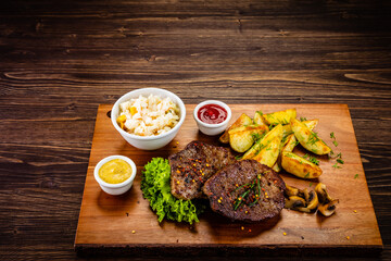 Fried beef sirloin with potatoes and vegetables on wooden table