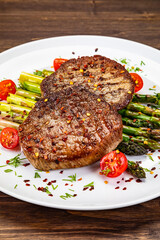 Barbecued beef steak with green asparagus on wooden table
