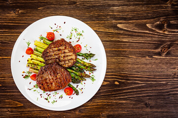 Barbecued beef steak with green asparagus on wooden table
