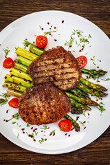 Barbecued beef steak with green asparagus on wooden table
