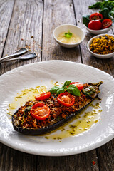 Roasted aubergine stuffed with minced meat and cheese on wooden table
