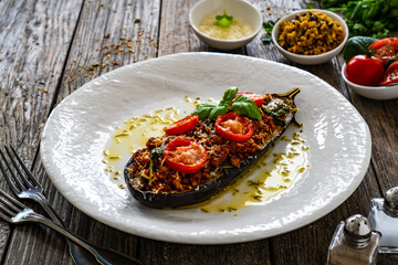 Roasted aubergine stuffed with minced meat and cheese on wooden table
