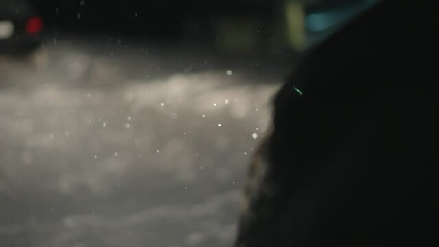 Snow storm in winter city, falling snow flakes illuminated by jammed car headlights. Slow motion