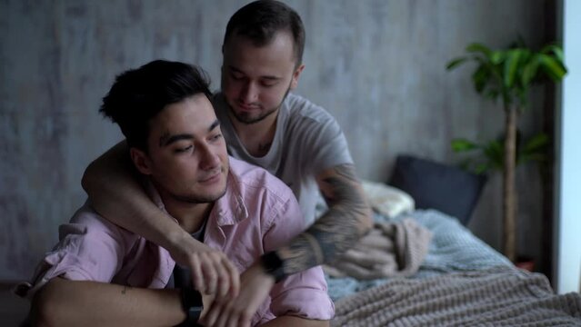 lgbt, same-sex relationships and homosexual concept - close up of pleasantly looking male partner hugging from behind his dominant friend, comforting him after quarrel.