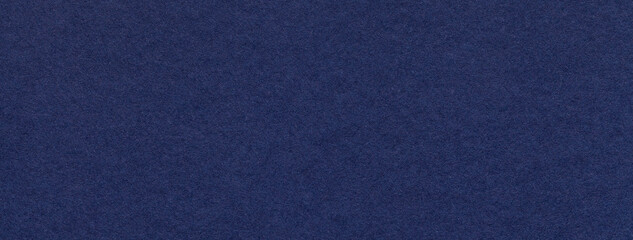 Texture of old navy blue color paper background, macro. Structure of a vintage craft dark denim...