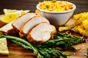 Sliced tasty roast chicken breast, green asparagus and cabbage on wooden table 