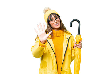 Young caucasian woman with rainproof coat and umbrella over isolated chroma key background counting five with fingers
