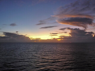 Breathtaking sunrise sunset dusk dawn twilight scenery over ocean with silhouettes of people and boats yachts seen panoramic view from cruiseship cruise ship liner during Caribbean cruising