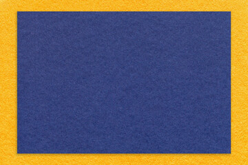 Texture of craft navy blue color paper background with yellow border, macro. Vintage dense kraft denim cardboard