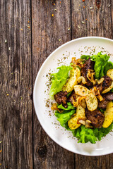 Fried liver with apples and onion on wooden table
