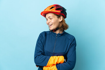 Young cyclist woman isolated on blue background looking to the side and smiling