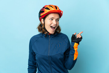 Young cyclist woman isolated on blue background intending to realizes the solution while lifting a finger up