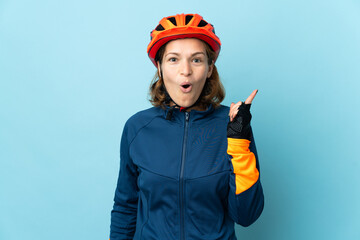 Young cyclist woman isolated on blue background intending to realizes the solution while lifting a finger up