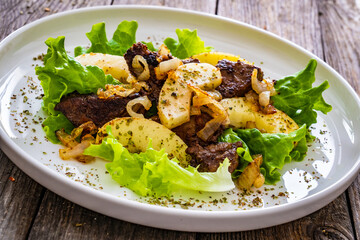 Fried liver with apples and onion on wooden table
