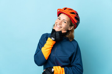 Young cyclist woman isolated on blue background happy and smiling