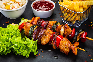 Chicken skewers - grilled meat with French fries on wooden background
