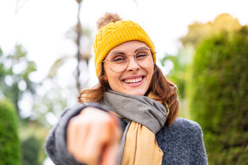 Brunette woman wearing winter jacket at outdoors points finger at you with a confident expression