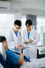 Fototapeta premium Hospital Ward Male and Femle Professional Asian Doctors Talk with a Patient, Give Health Care Advice, Recommend Treatment Plan with Advanced Equipment .