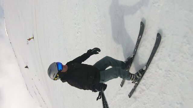 Selfie of skier carving on new slope on Popova Sapka in Macedonia on sunny day, cinematic slow motion vertical footage