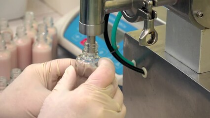 Semi-automatic filling of vials with the cosmetics cream at the factory.