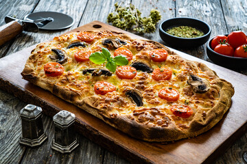Pinsa Romana with mozzarella and vegetables on wooden table
