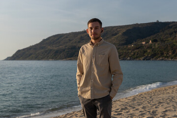 young man in a shirt, looking at the camera with a handsfree on the beach