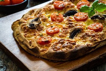 Pinsa Romana with mozzarella and vegetables on wooden table
