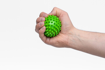 Zielona piłka z kolcami wciskana w dłoń jako forma rehabilitacji nadgarstka