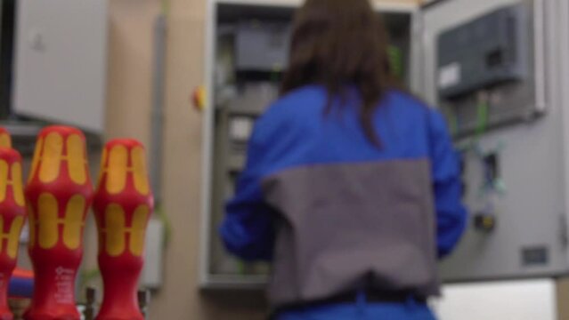 female electrician working with screw driver on switch cabinet