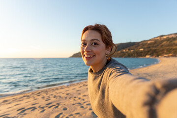 redhead woman taking a selfie on the beach