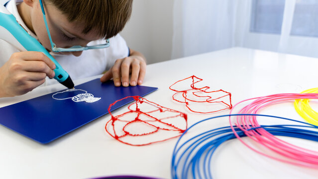a boy plays with a 3d pen