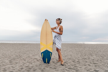 Fototapeta na wymiar Portrait of a surfer woman posing with surfboard on a beach