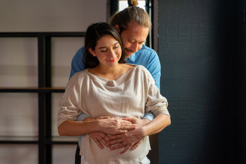 Happy Caucasian pregnancy woman and husband hugging each other and dancing together in bedroom at...