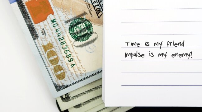 cash dollar money with text written TIME IS MY FRIEND , IMPULSE IS MY ENEMY - to remind oneself a financial essential motto to save as early as one can and be careful of impulse spending