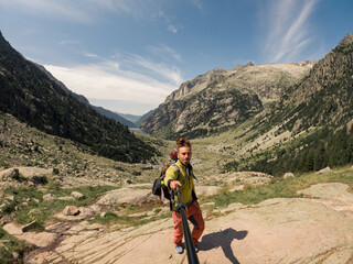 Fototapeta premium person walking on the mountain with a movie sky, making a self-portrait, with mountains and meadows in the background