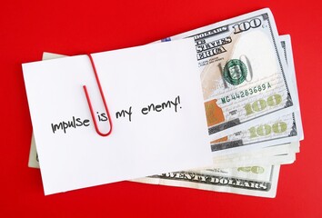 An amount of cash dollars money clipped with a white note pad written IMPULSE IS MY ENEMY , concept...