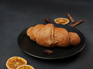 Delicious, freshly baked Croissant Lying on a black Plate against a black background